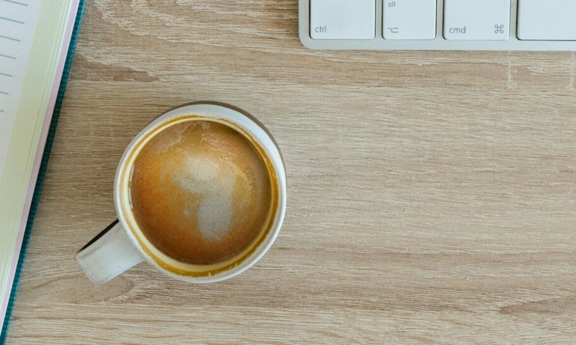 coffee latte near white wireless keyboard and Apple EarPods on the table photography