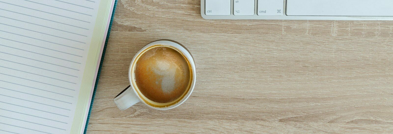 coffee latte near white wireless keyboard and Apple EarPods on the table photography