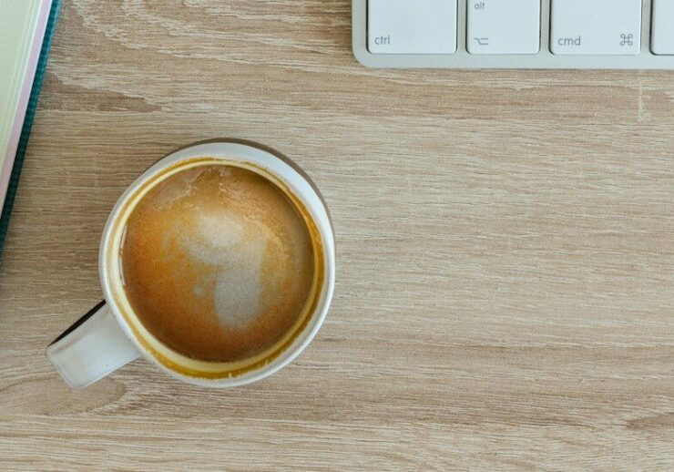 coffee latte near white wireless keyboard and Apple EarPods on the table photography