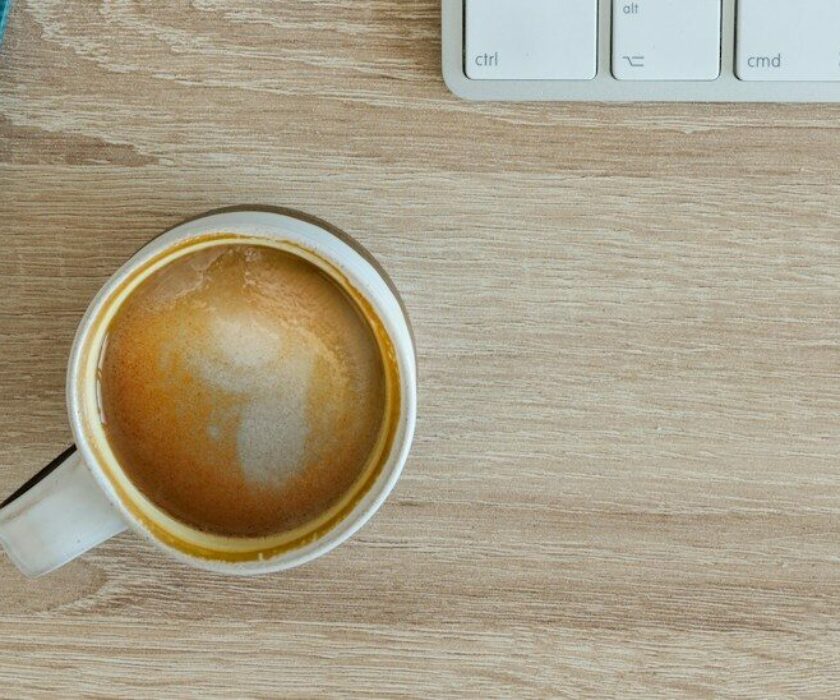 coffee latte near white wireless keyboard and Apple EarPods on the table photography